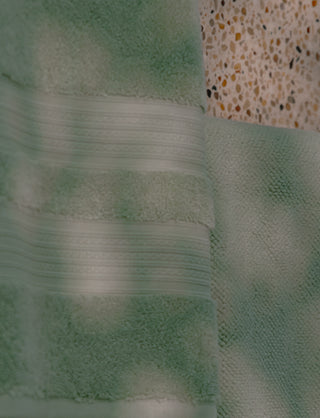 Green bath towel on a terrazzo floor.