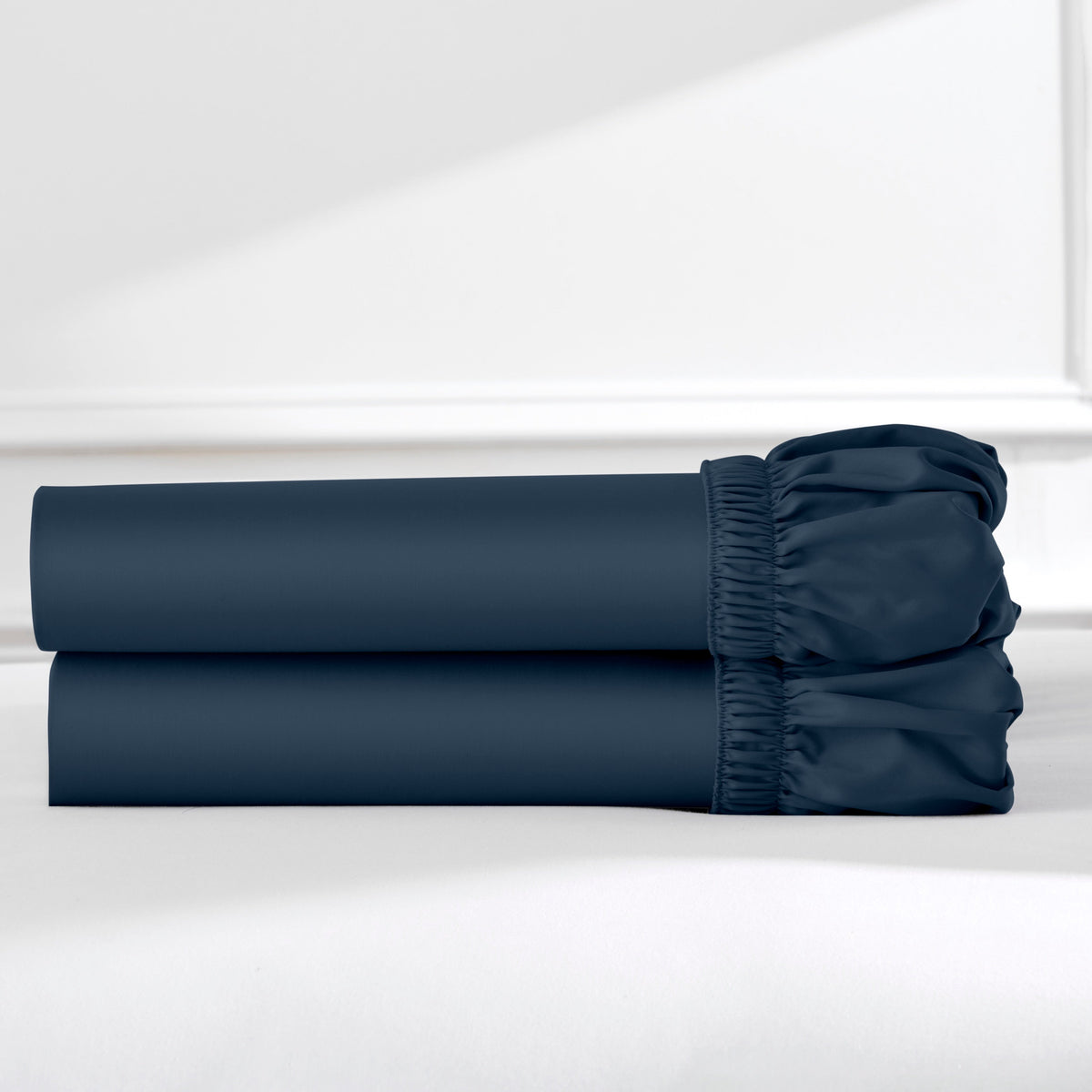 Two dark blue cotton fitted sheets folded and stacked.