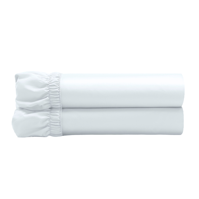 White fitted sheets folded and stacked, showing gathered elastic edges.