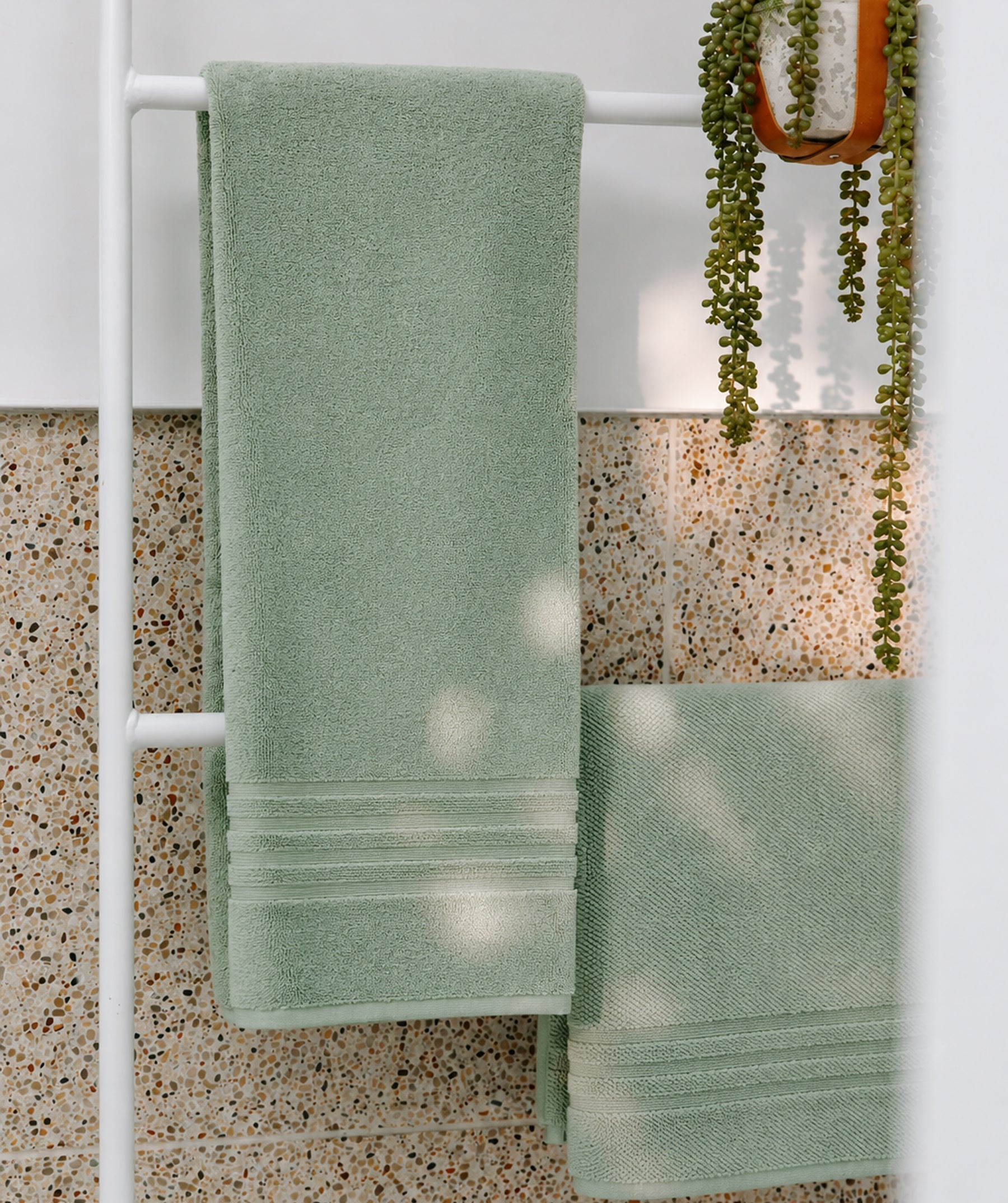 Light green bath towel hanging on a towel rack in a modern bathroom.
