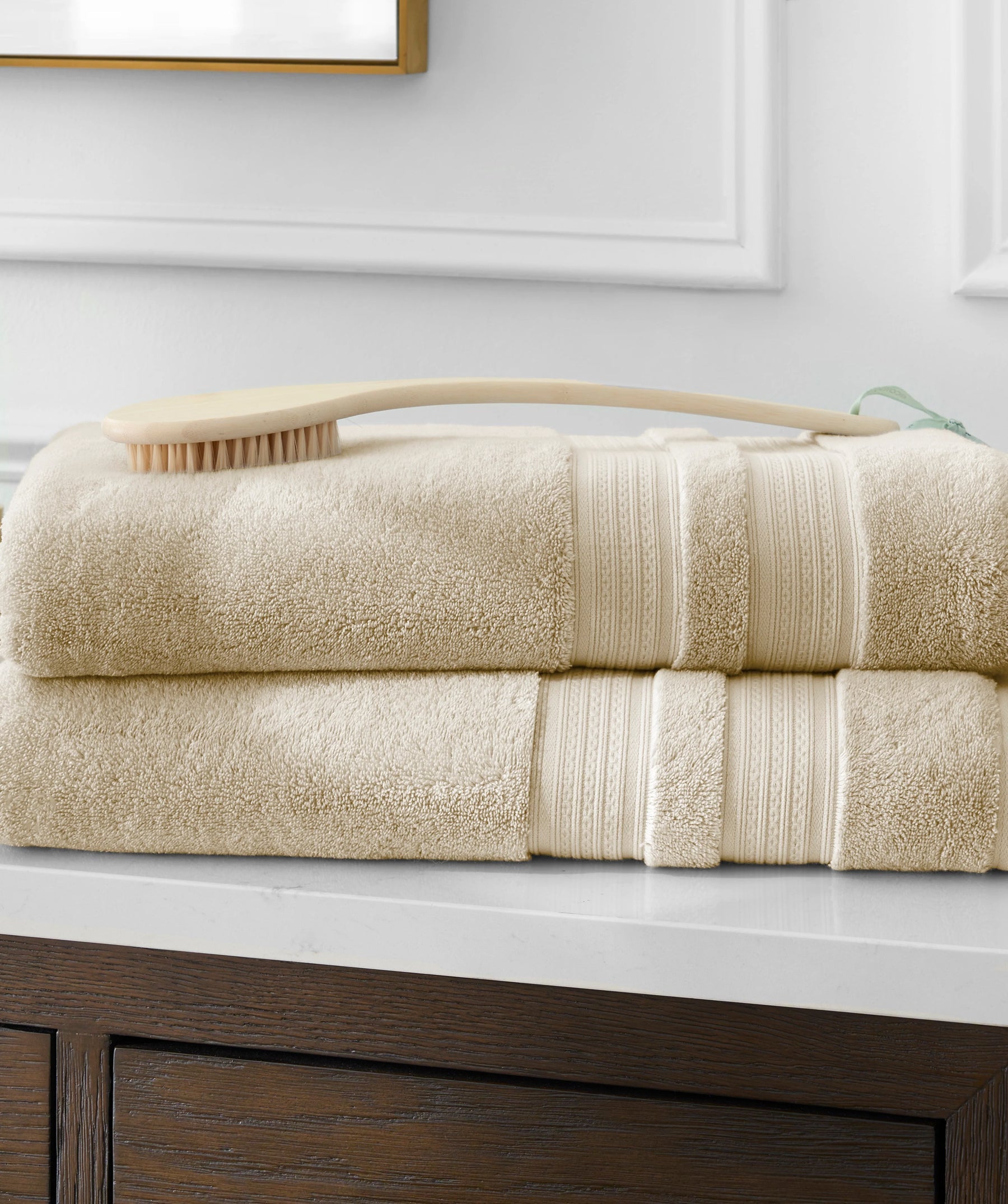 Stack of yellow bath towels with a dry body brush on a bathroom vanity.