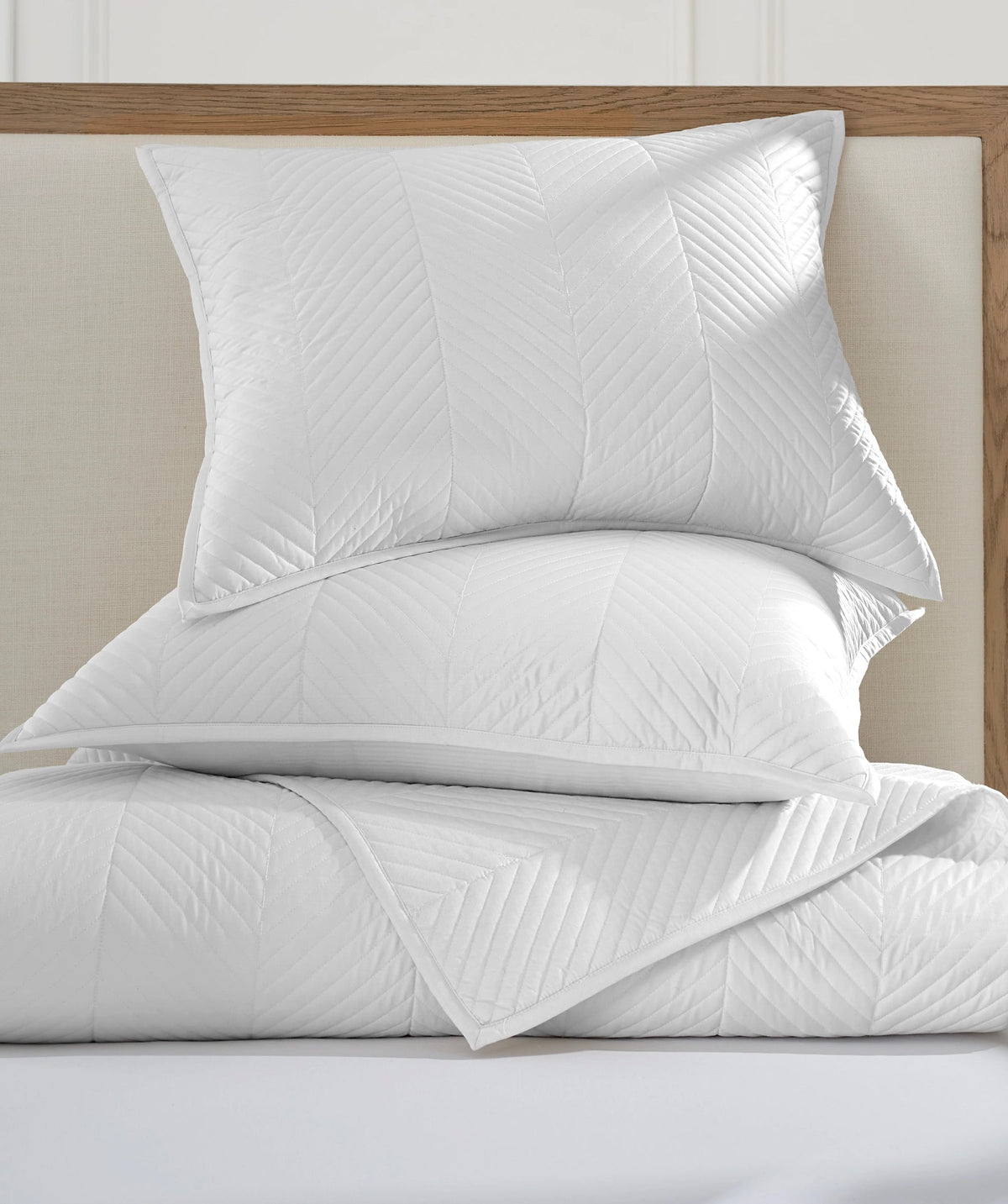 Folded white herringbone stitch coverlet set.