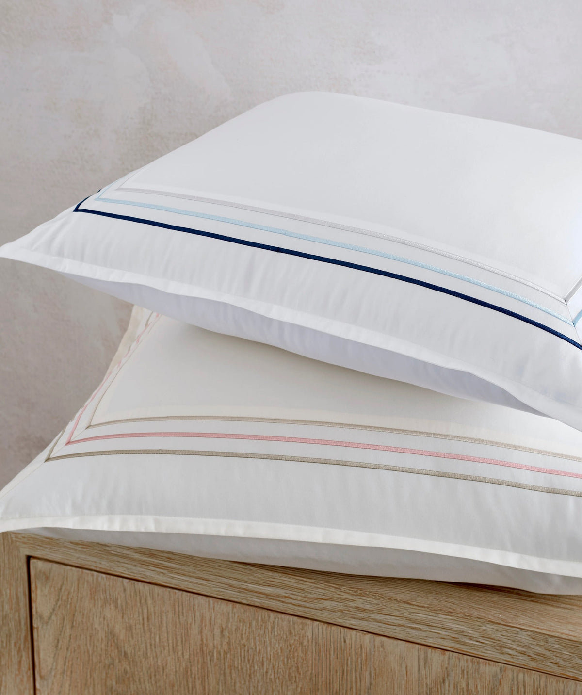 White pillow sham with embroidered border trim.