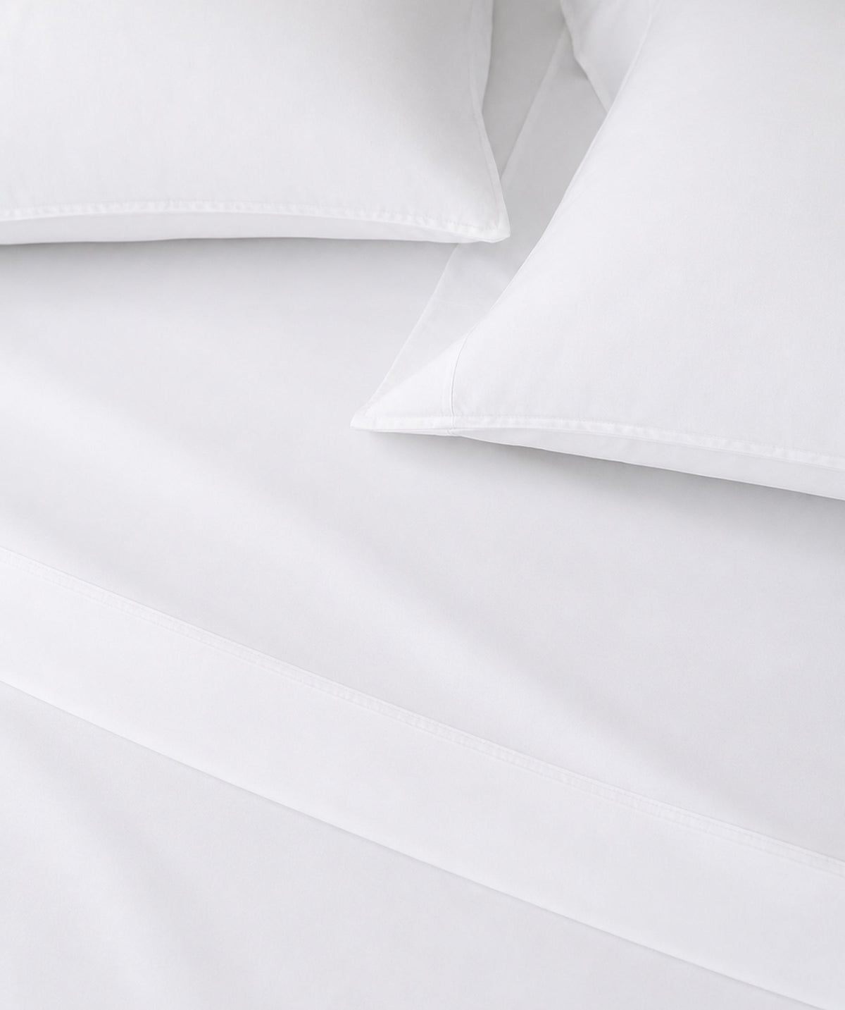 Close-up of crisp white sheets and pillowcases with clean stitched hem details.