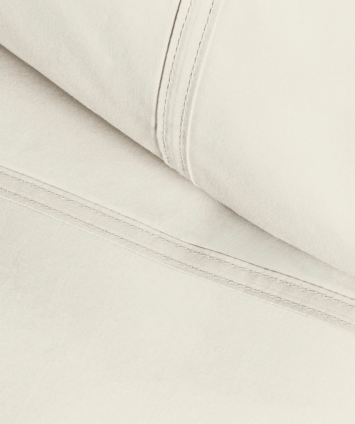 Close-up of ivory pillowcase fabric highlighting smooth texture and stitched seams.
