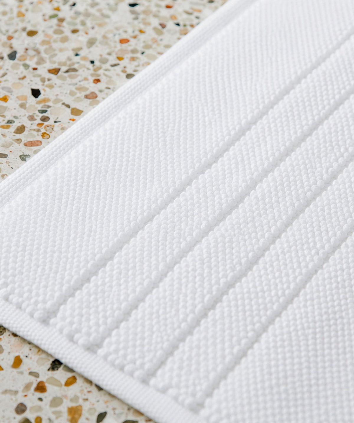 Close-up of the white bath mat's textured surface and stripe details.