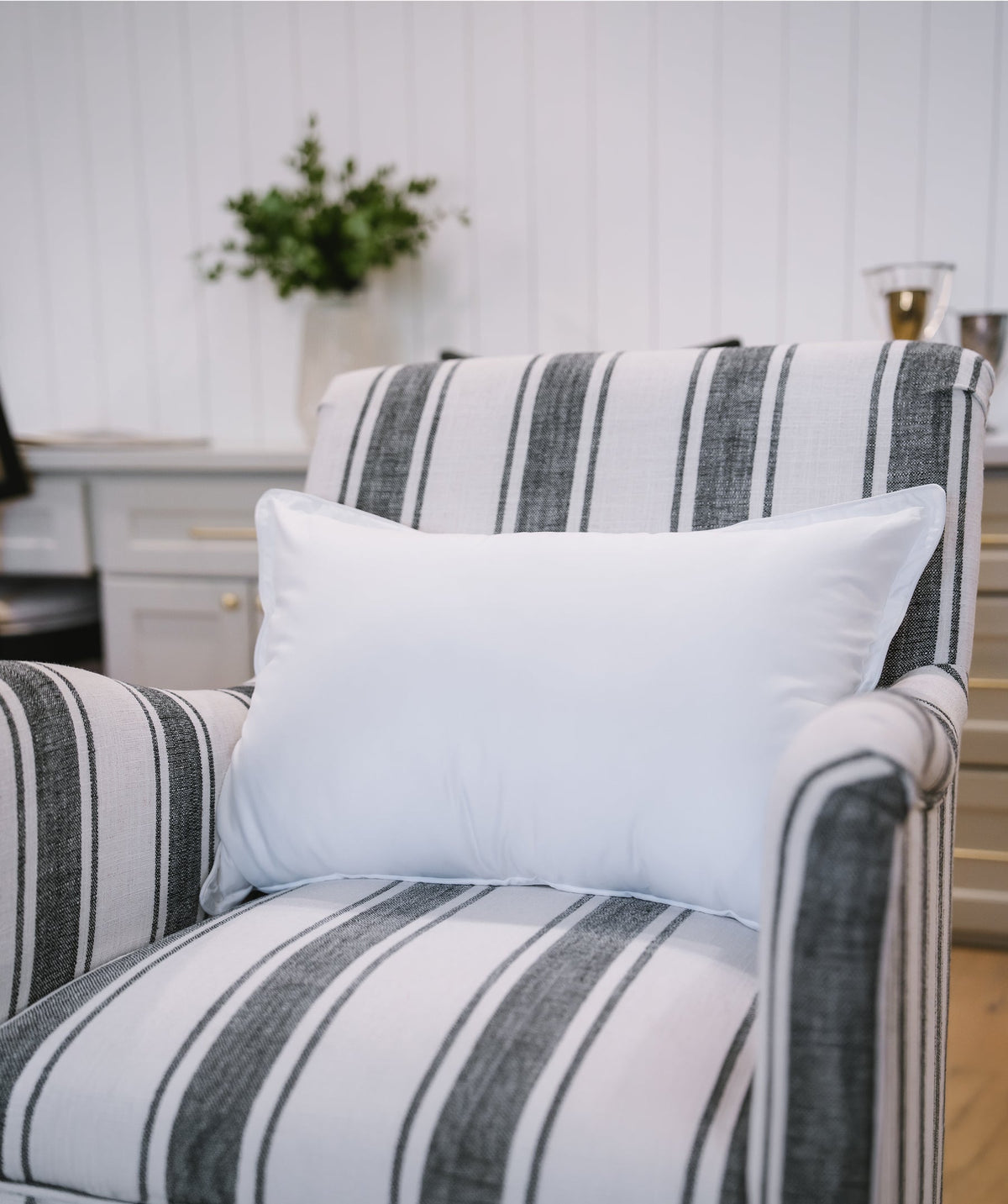 White bolster pillow styled on a striped accent chair.
