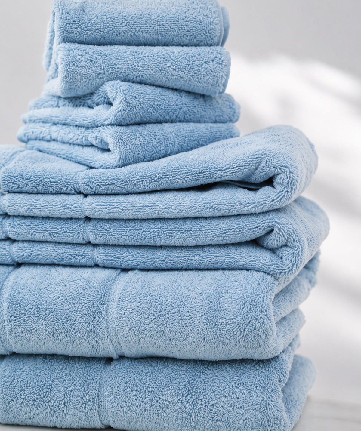 Stack of blue Egyptian cotton bath towels in assorted sizes.