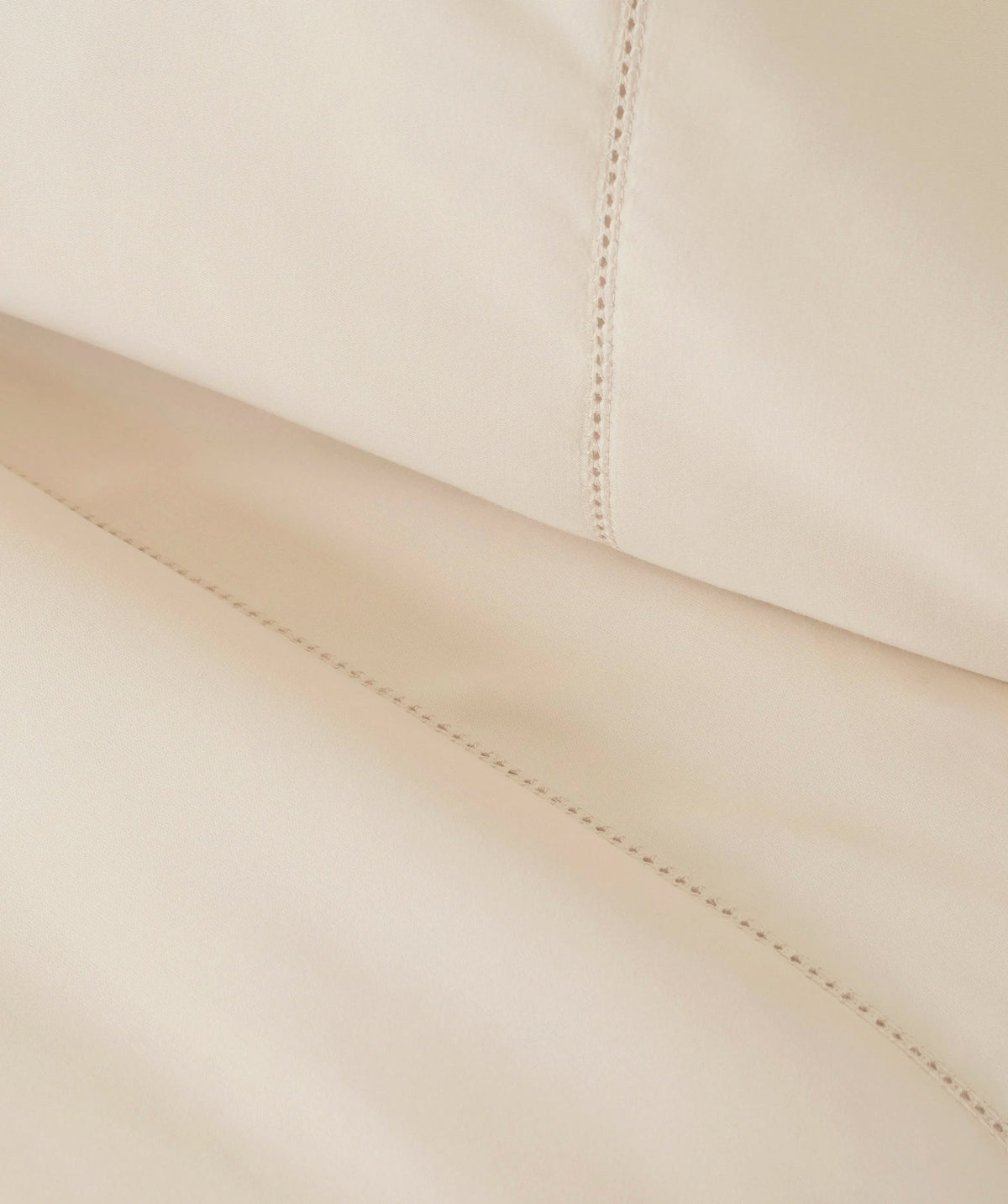 Close-up of ivory pillowcase fabric highlighting decorative stitched detailing.