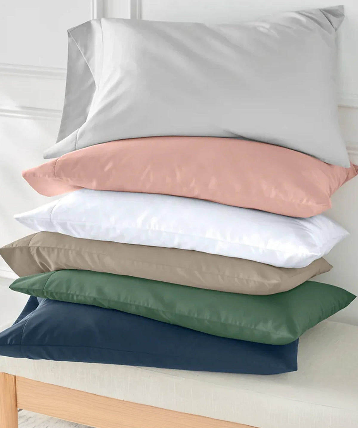 Stack of pillowcases in white, blush pink, taupe, green, and navy.