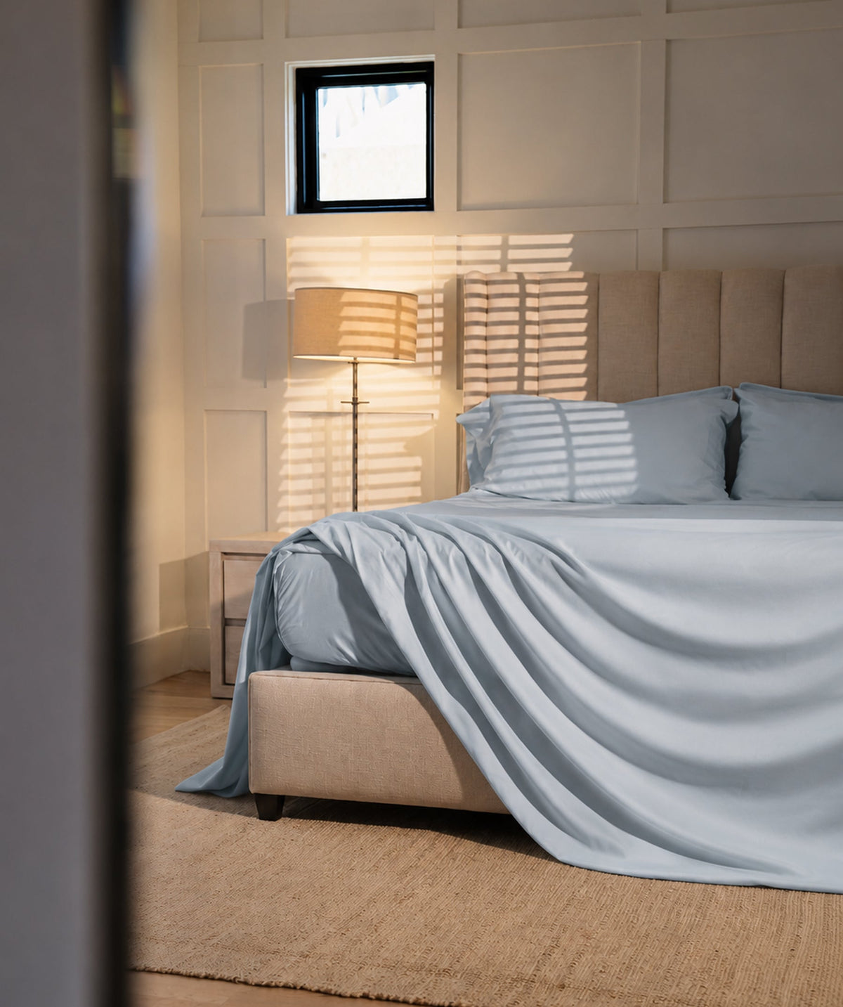 Light blue sheet set styled on a bed in a sunlit neutral bedroom.
