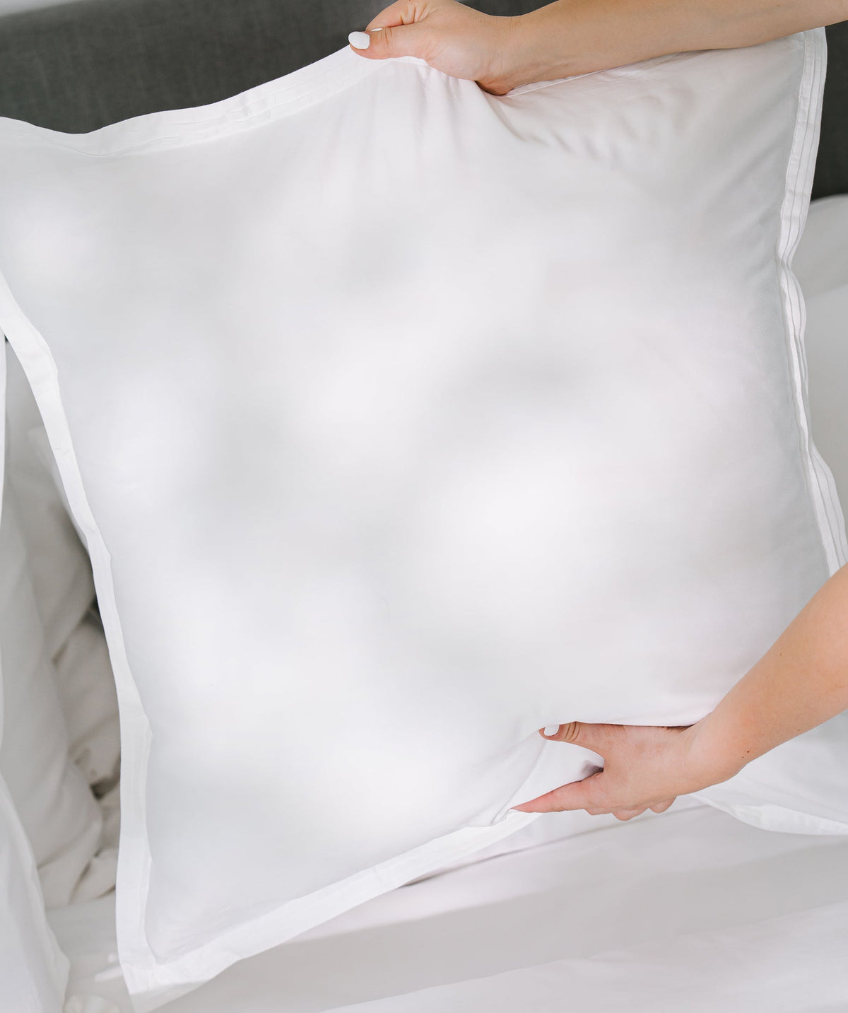 Hands holding a white solid Euro sham.
