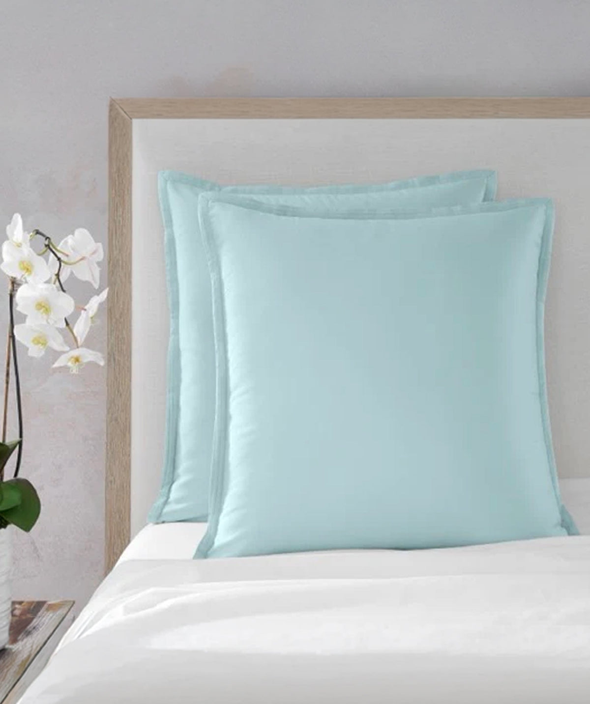 Pastel blue solid Euro shams styled on a bed.