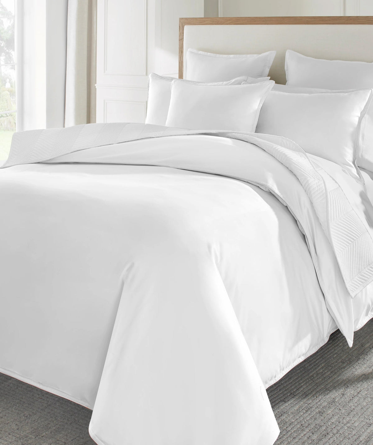 White comforter set styled on a bed with matching pillow shams and decorative pillows.