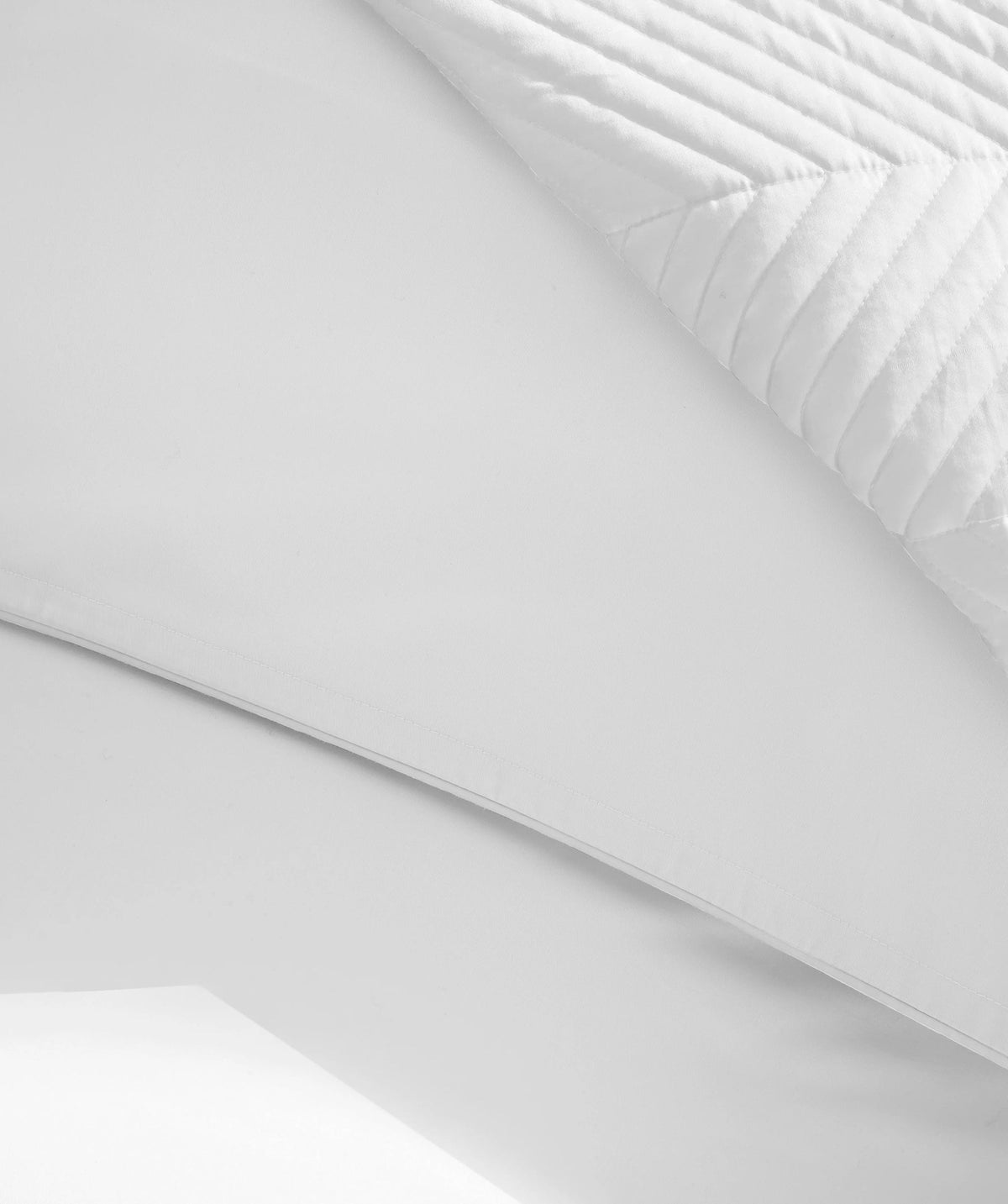 Close-up of white comforter with smooth fabric and herringbone quilt.