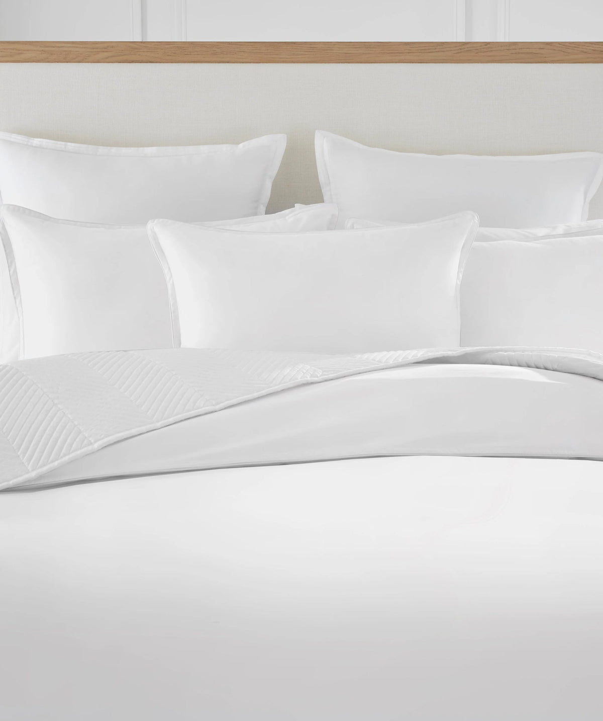White comforter set with matching pillow shams and decorative pillows.