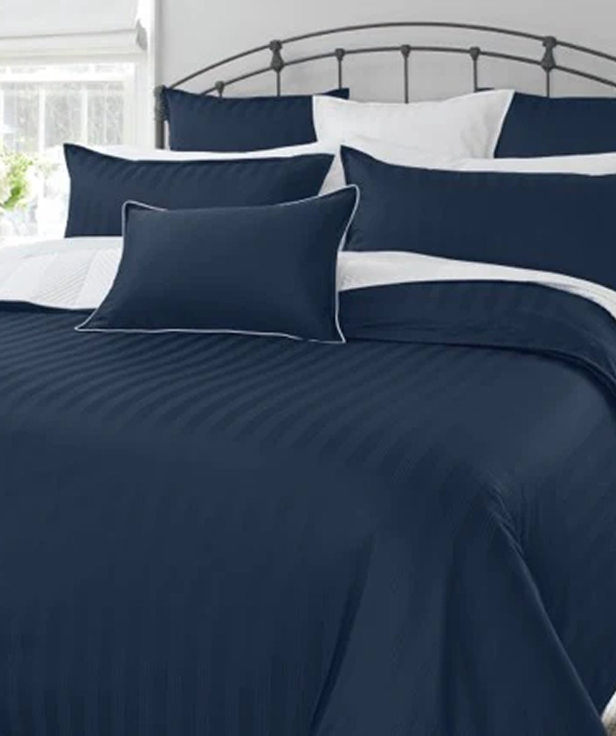 Navy blue bedding set with white accents on a bed.