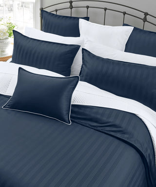 Navy blue and white striped bedding set on a bed with a metal headboard.